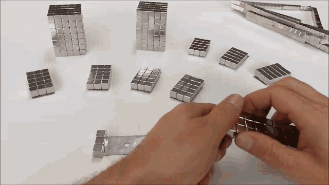 a person is holding a piece of metal that looks like a tetris piece