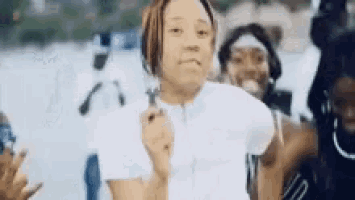 a woman in a white shirt is standing in front of a group of people and holding a lighter .