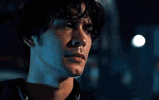 a close up of a man 's face with a tear running down his cheek in a dark room .