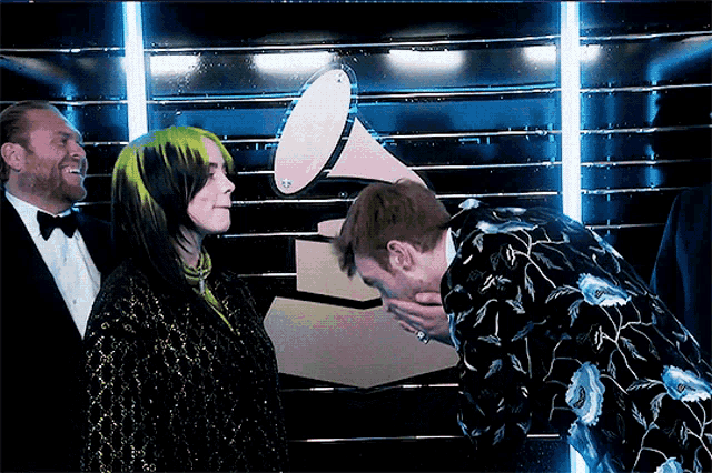 a man covering his face with his hand while standing next to a woman