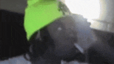 a man wearing a neon green hat is smoking a cigarette .