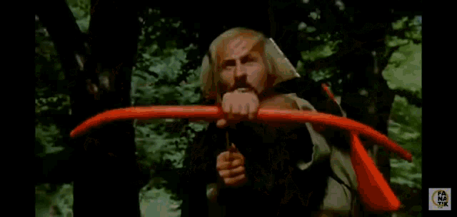 a man in a white shirt is holding a bow and arrow .