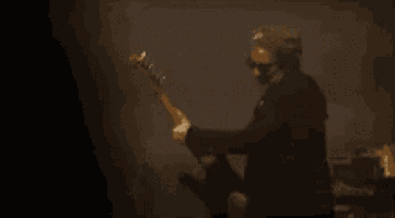 a man in a suit is playing a guitar in a dark room .