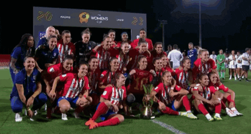 a women 's soccer team poses for a photo with a trophy