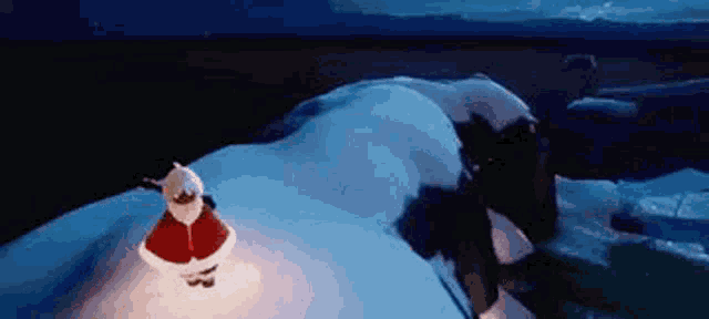 a person in a santa claus costume is standing on top of a snow covered hill .