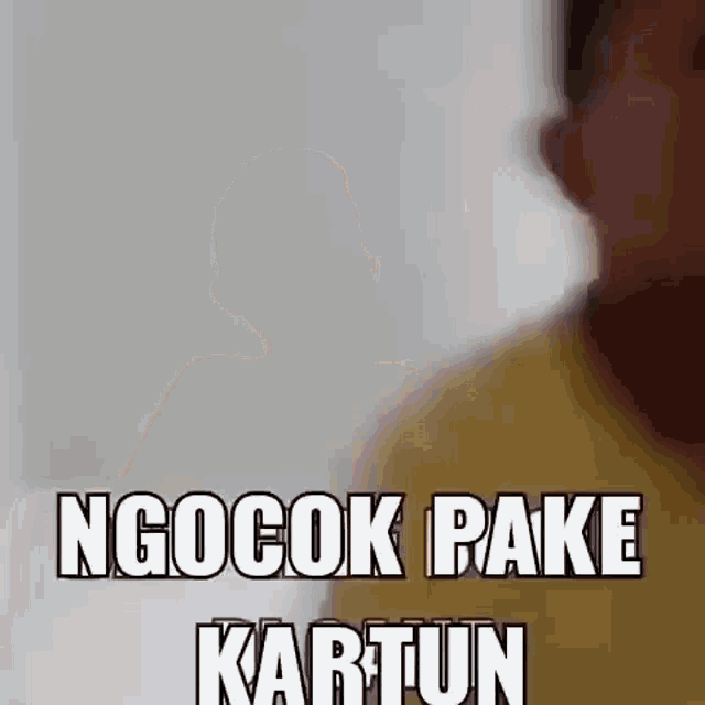 a man in a yellow shirt is standing in front of a white wall and says ngocok pake kartun .