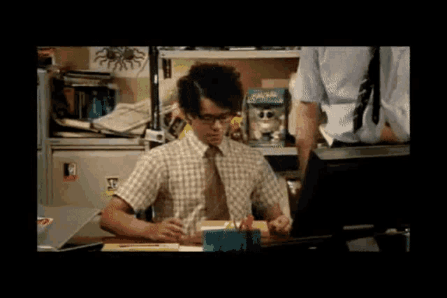 a man is sitting at a desk with a sticker on the wall that says ' a ' on it