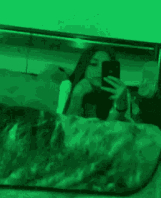 a woman is taking a picture of herself in a mirror while laying in bed .