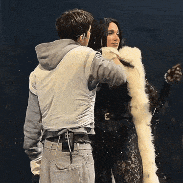 a man is putting a fur coat on a woman 's head .