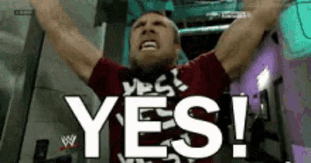 a man is raising his arms in the air and saying yes !