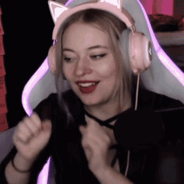a woman wearing pink cat ears headphones is sitting in a chair .