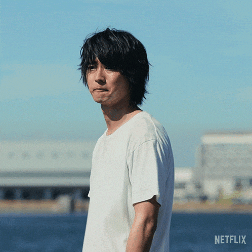 a man in a white t-shirt is standing in front of a body of water with a netflix logo behind him