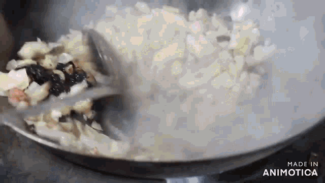 a pan of food is being stirred with a spoon and the words made in animatica are visible in the corner