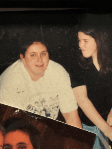two women are posing for a picture and one has a t-shirt that says ' i love you ' on it