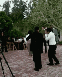 a group of people are dancing on a brick pavement outside