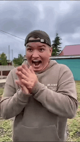 a man wearing a hat and a sweatshirt that says be a winner on it is clapping his hands .