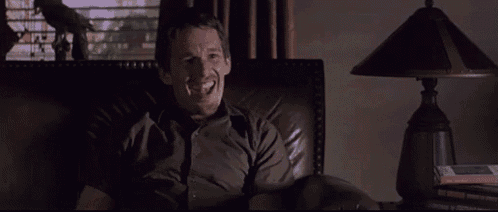a man is smiling while sitting in a chair in a dark room