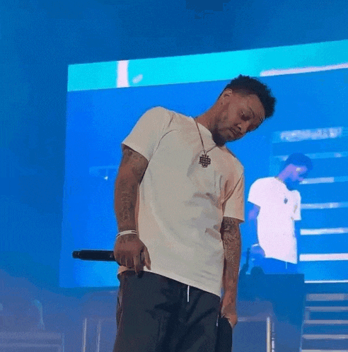 a man in a white shirt is standing on a stage with a microphone in his hand