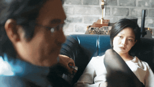 a man and a woman are sitting on a couch and the man is holding a rubik 's cube