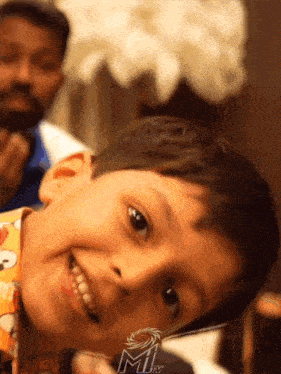 a young boy is smiling in front of a sign that says mitv