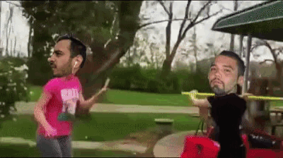 a man in a pink shirt with the number 12 on it is running with another man