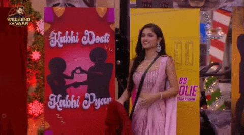 a woman in a pink dress is standing in front of a sign that says kabhi dosti kabhi pyar