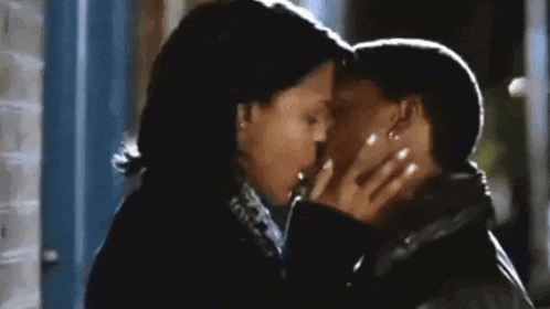 a man and a woman are kissing each other in front of a blue door .