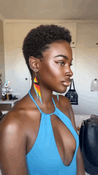 a woman wearing a blue halter top and earrings .