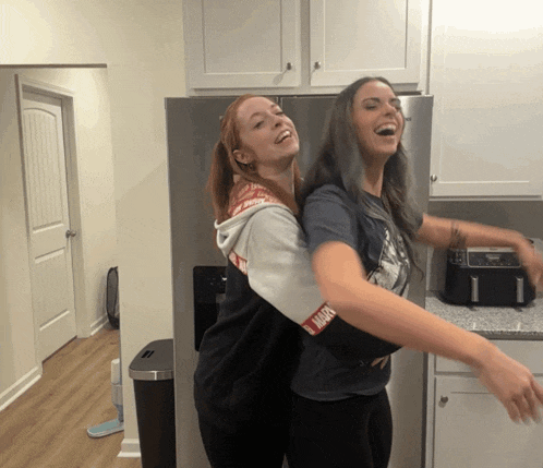 a woman in a marvel shirt is hugging another woman in a kitchen
