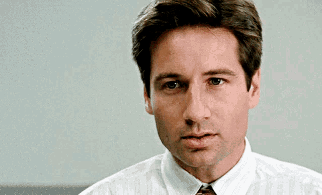 a man in a striped shirt and tie looks at the camera