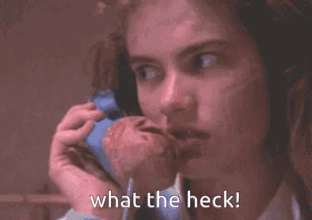 a woman talking on a phone with the words what the heck