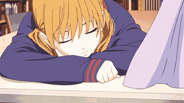 a girl with blonde hair is sleeping on a table