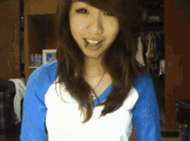 a girl wearing a blue and white shirt is smiling for the camera
