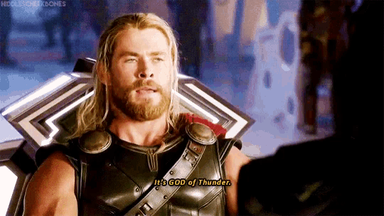 a man with a beard is talking to another man in a room .