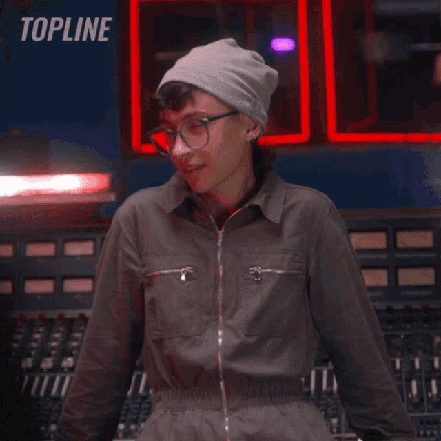 a person wearing a hat and overalls is standing in front of a sign that says topline