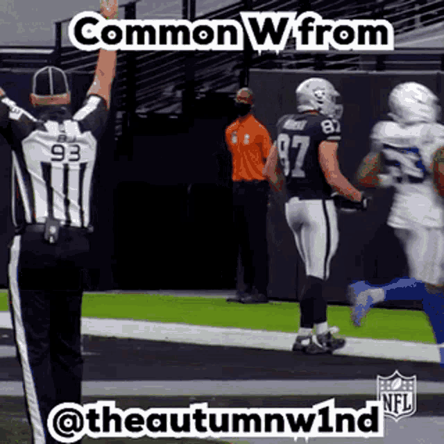 a referee with the number 93 on his back is standing on a football field with two football players .