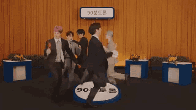 a group of men in suits are dancing in front of a sign that says 90 on it