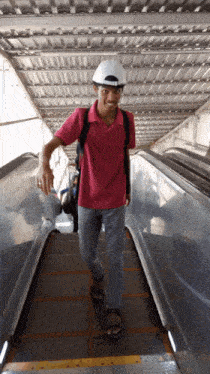 a man wearing a white hat and a pink shirt is walking down an escalator