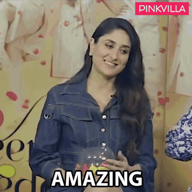 a woman in a denim jacket is smiling and holding a glass bowl with the word amazing written on it