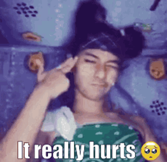 a man is laying on a bed with a bandage on his head and the words it really hurts .