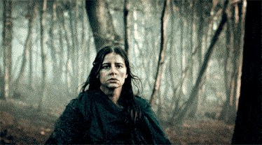 a woman with a scarf around her neck is sitting in the woods