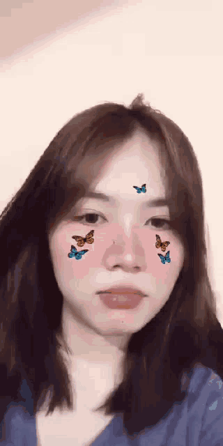 a woman with butterflies on her face and a blue shirt
