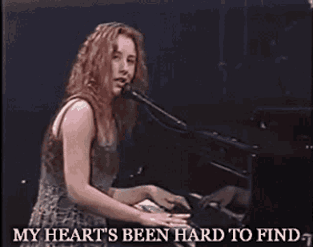 a woman singing into a microphone while playing a piano with the words my heart 's been hard to find below her