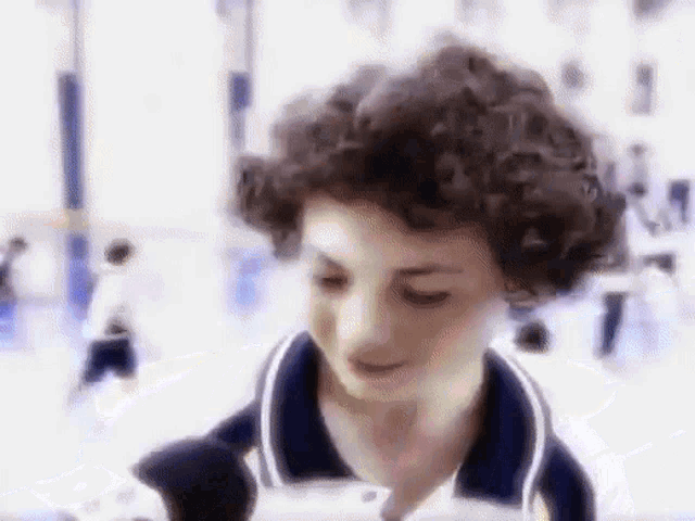 a young boy with curly hair is smiling and looking at something
