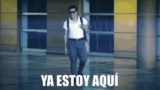 a man wearing sunglasses walks in front of a sign that says " ya estoy aqui "