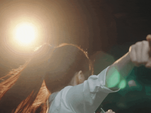 a woman with her arms outstretched in front of a light