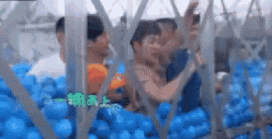 a group of people are playing in a pool of blue balls .