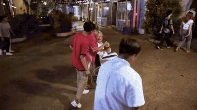 a woman in a wheelchair is being pushed by two men