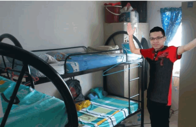 a man in a red and black shirt with the number 7 on it stands in front of a bunk bed