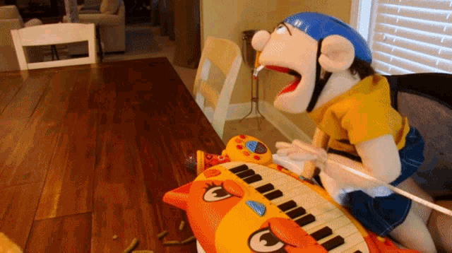 a puppet wearing a blue helmet sits on a piano